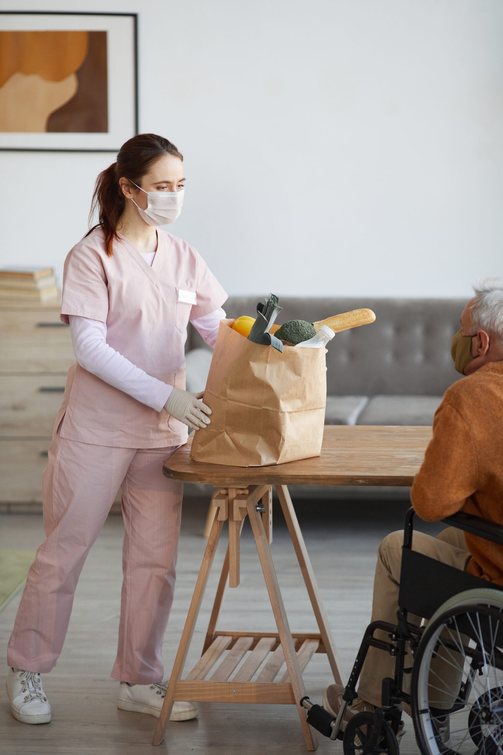 Caregiver delivering groceries to a senior man at home, illustrating flexible assistance with errands and daily needs.