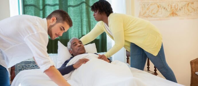 Caregiver assisting a senior man in bed, providing essential personal care and daily living support for safety.